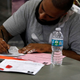 A man fills out a form during an event held by the Florida Rights Restoration Coalition (FRRC) to clear the fines and fees of dozens of Florida residents with past felony convictions, in Miami, Florida, on April 28, 2022. - Hundreds of thousands of returning citizens (people with past felony convictions) in Florida still owe fines and fees associated with their past convictions. These financial obligations create barriers to voting, accessing opportunities, getting driver’s licenses, and more.